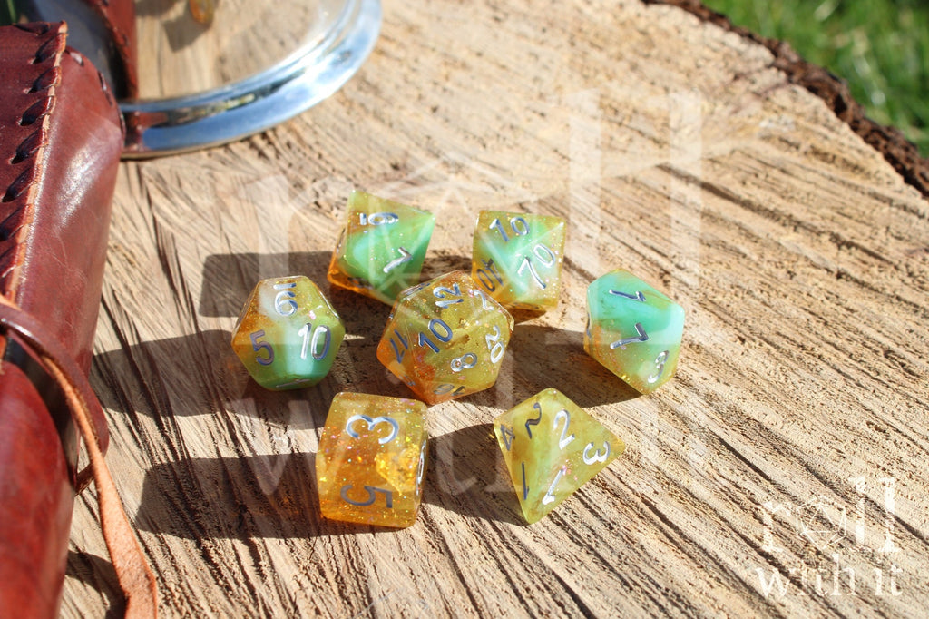 Set of colourful and glittery golden and teal polyhedral dice with silver numbers on a wooden surface