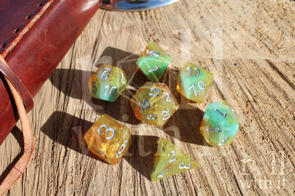 Set of colorful and glittery golden and teal polyhedral dice with silver numbers on a wooden surface