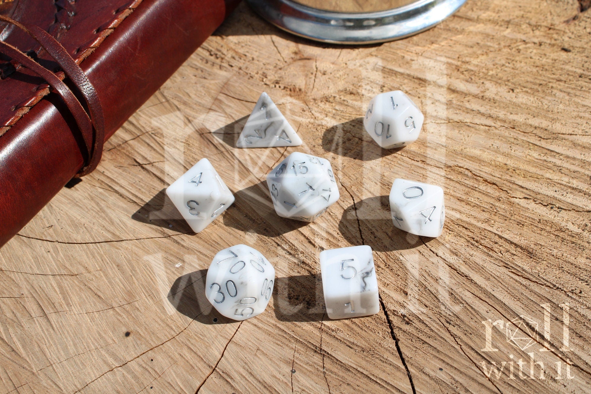 Granite white polyhedral DND dice with silver numbering on a wooden surface.