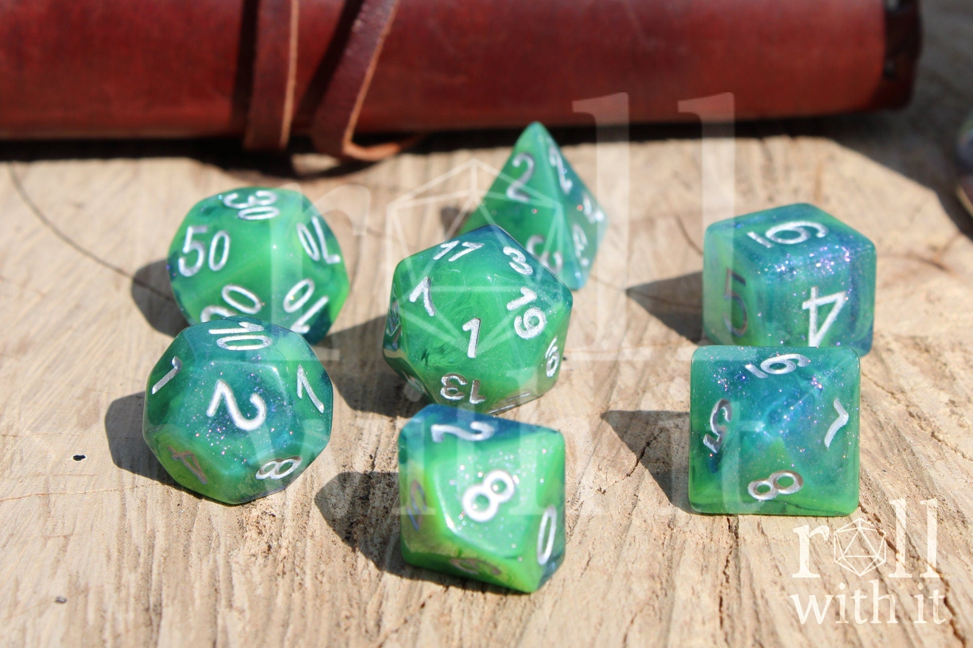 Set of green and blue glittery polyhedral dice with silver numbers on a wooden surface