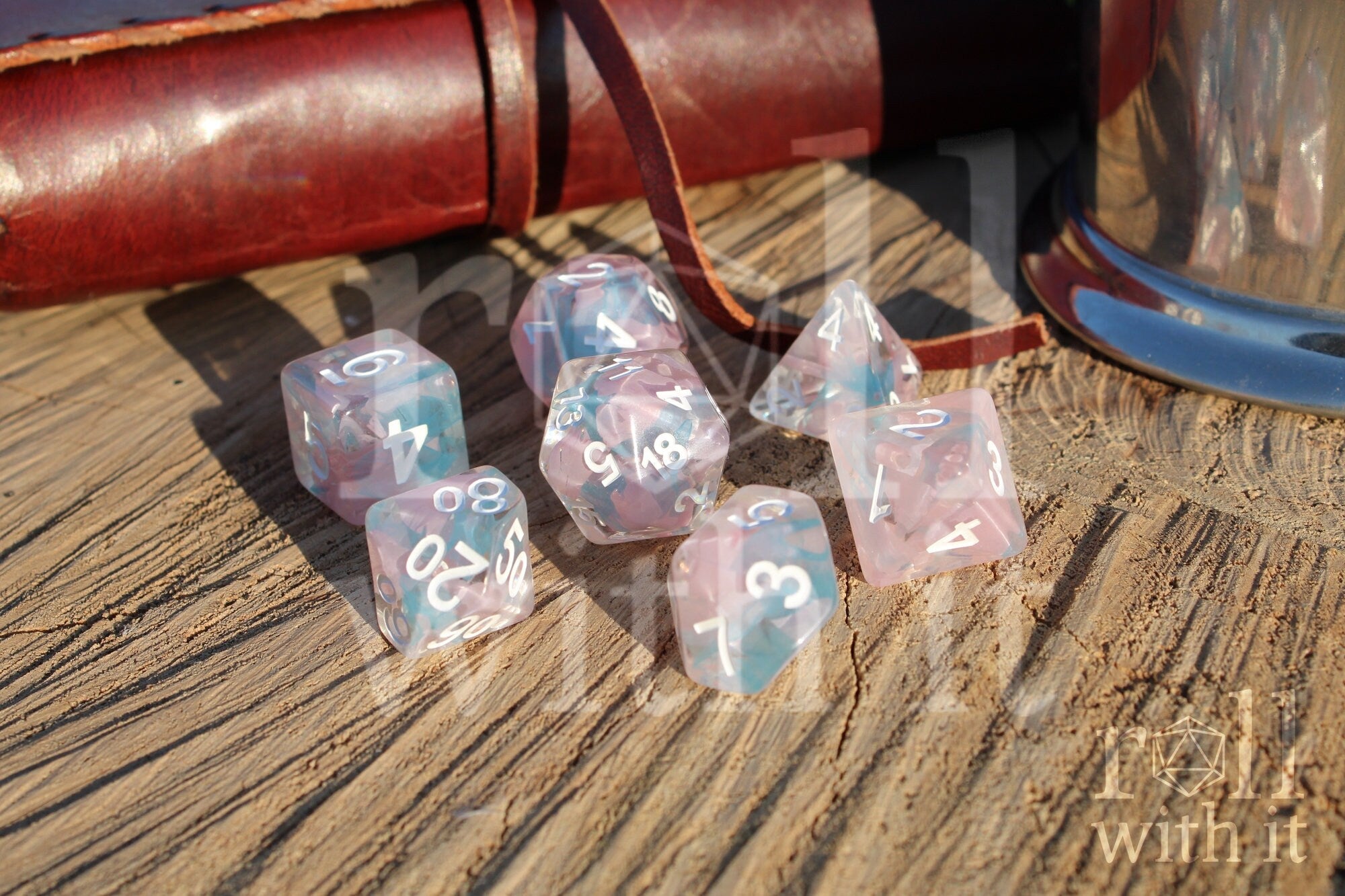Set of pink and pale blue translucent polyhedral DND dice on a wooden surface