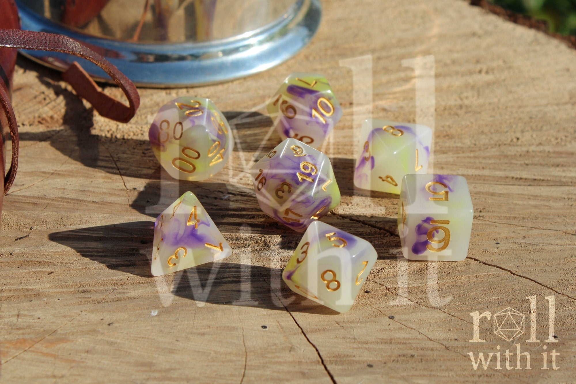Set of purple green and creamy white dice with gold numbers on a wooden surface