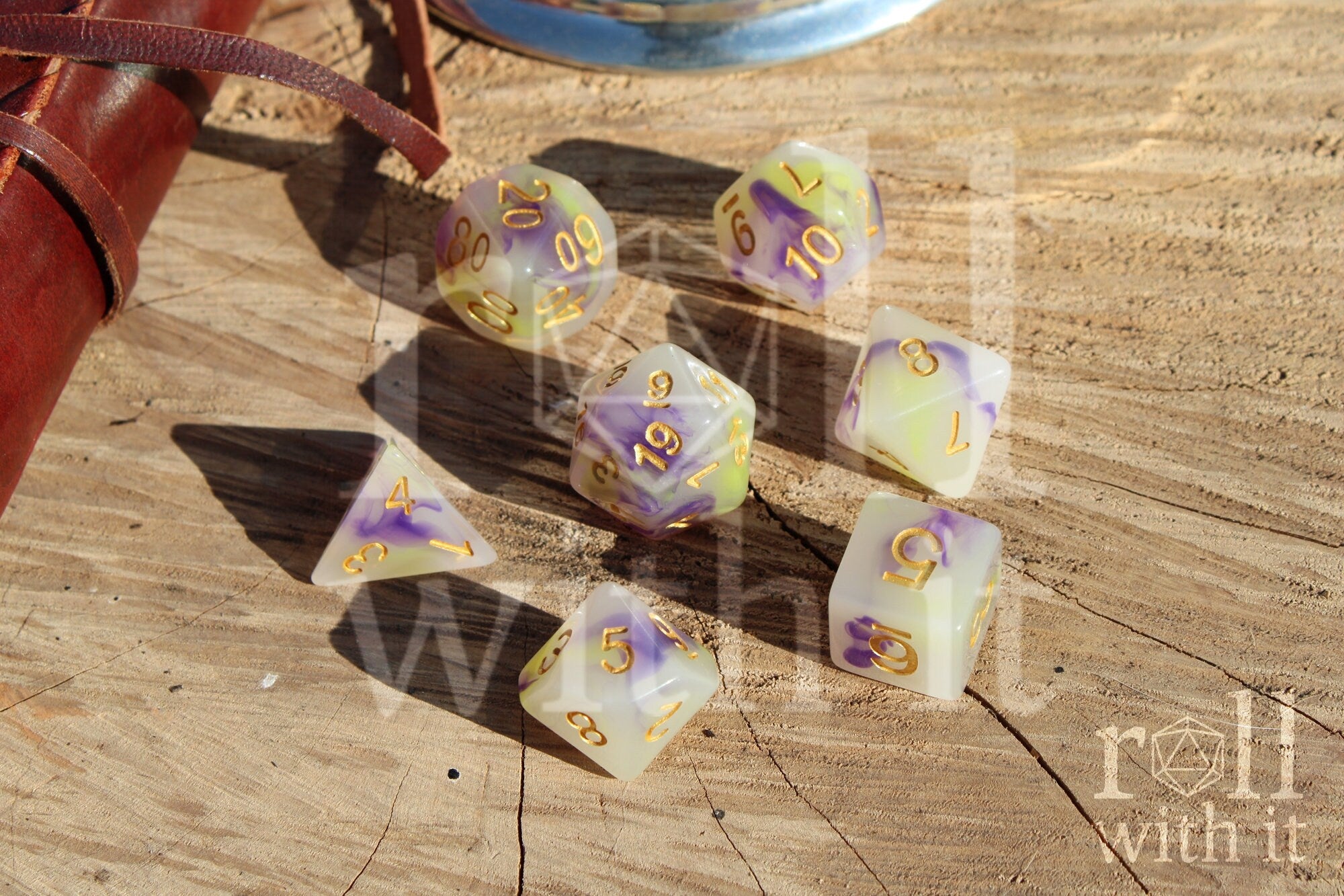 Set of purple green and creamy white dice with gold numbers on a wooden surface
