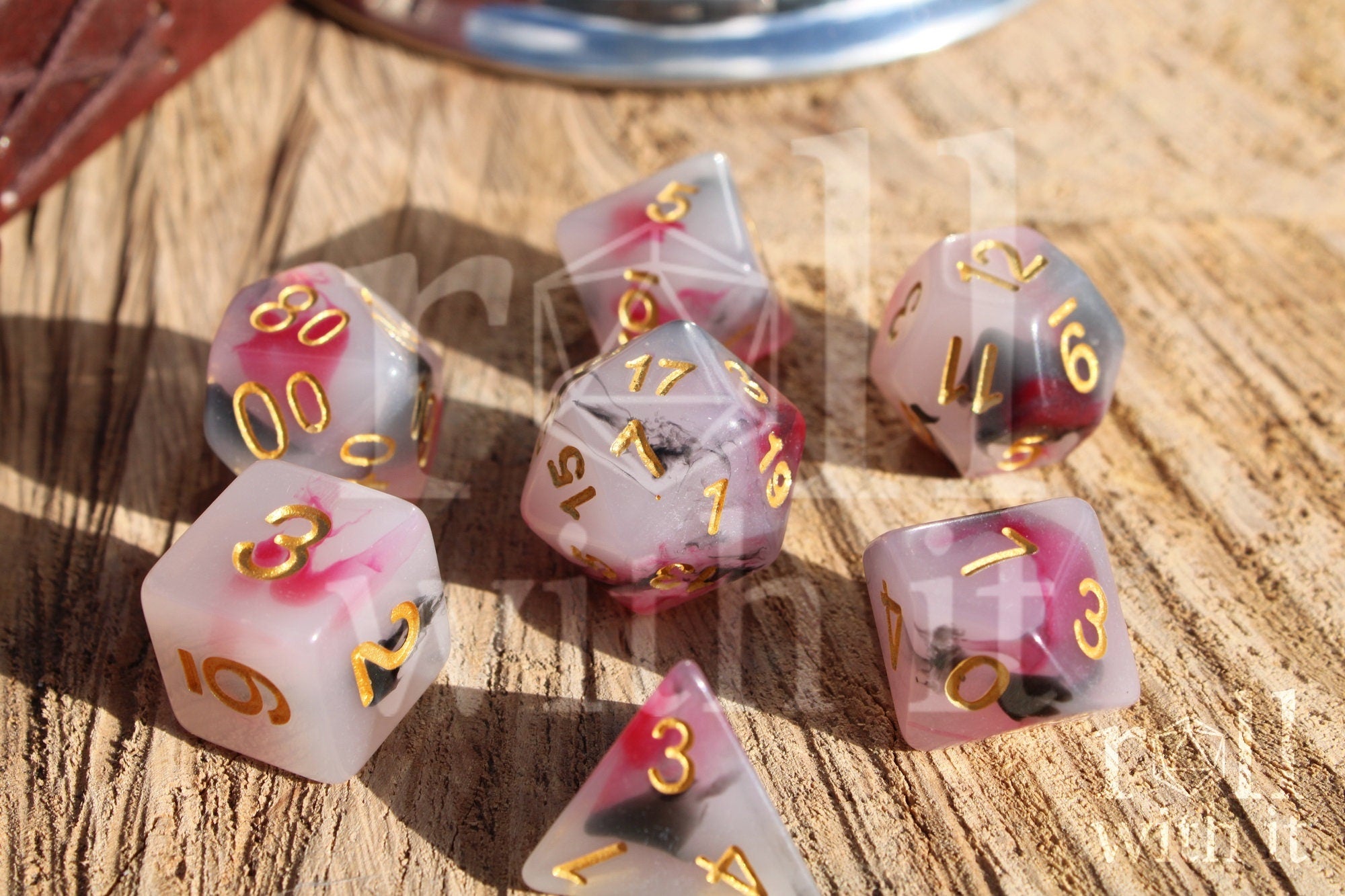 Set of black, red, and creamy white roleplaying dice with marbled design and gold numbers on a wooden surface