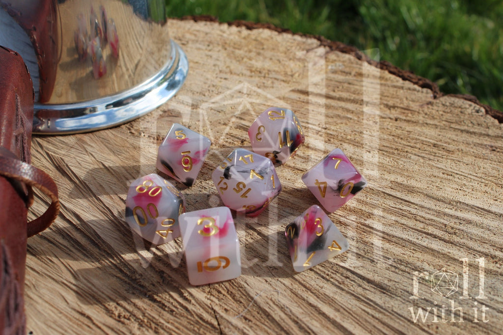 Set of black, red, and creamy white roleplaying dice with marbled design and gold numbers on a wooden surface