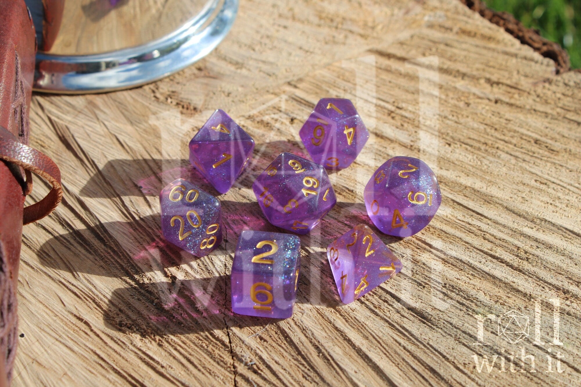Set of glittery purple polyhedral dice with gold numbers on a wooden surface
