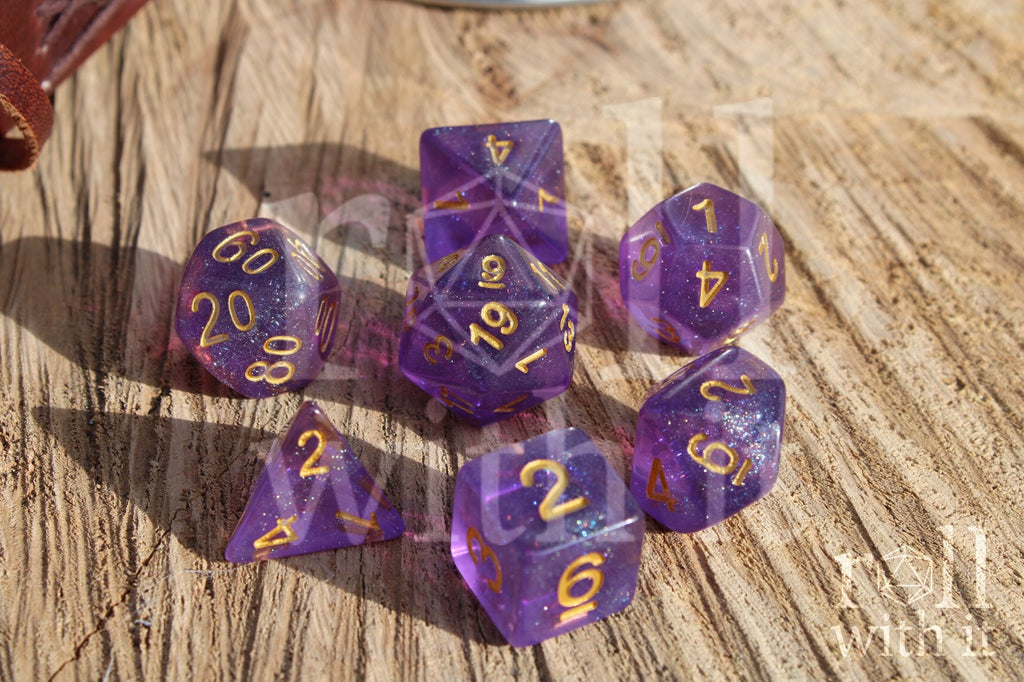 Set of glittery purple polyhedral dice with gold numbers on a wooden surface