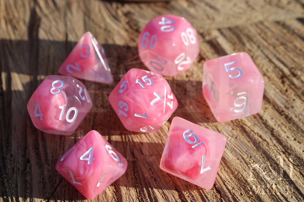 Set of cloudy pink and clear polyhedral roleplaying dice with white numbers on a wooden surface