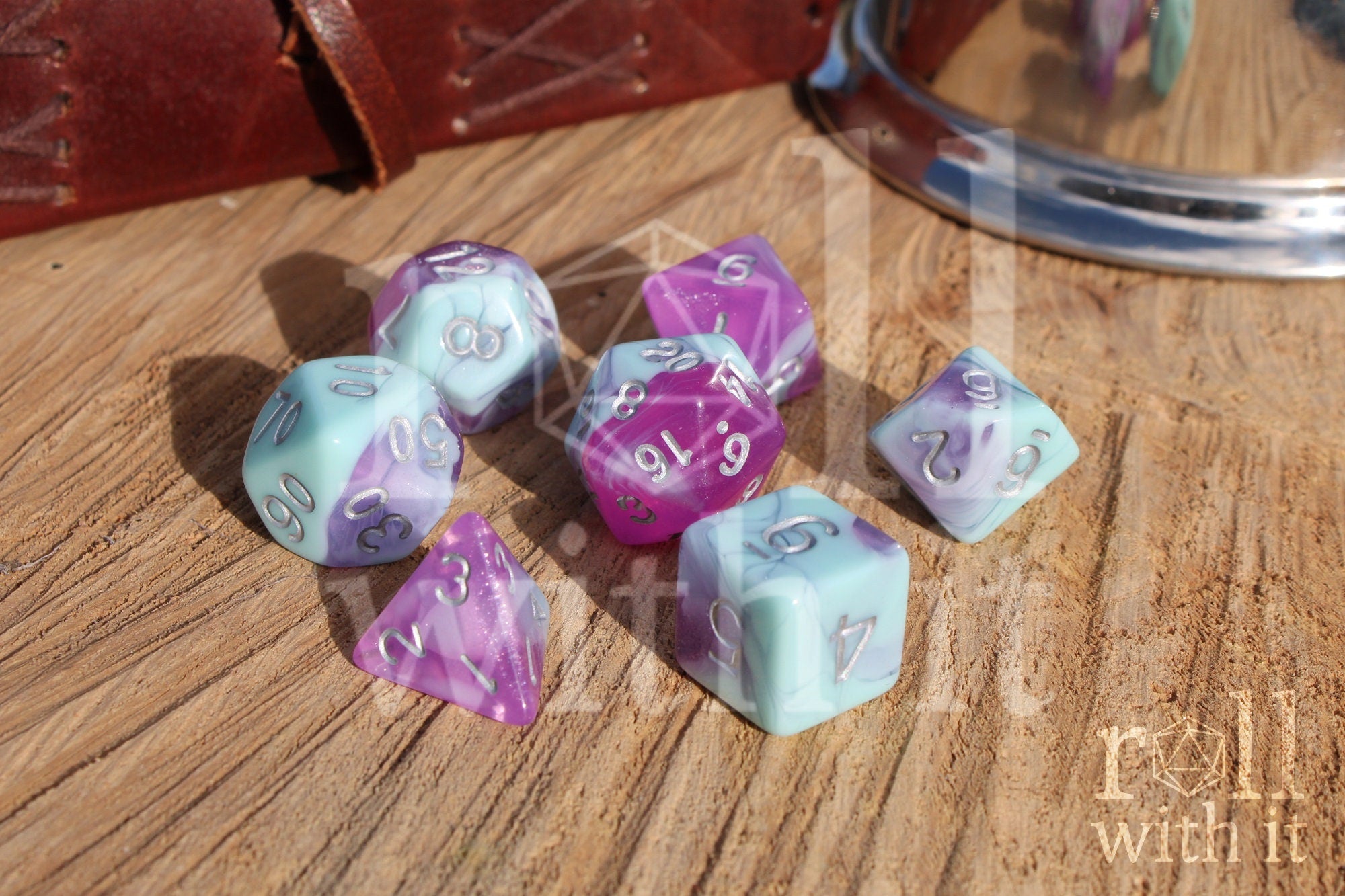 Set of 7 pastel blue marble and clear orchid purple polyhedral DND roleplaying dice on a wooden surface