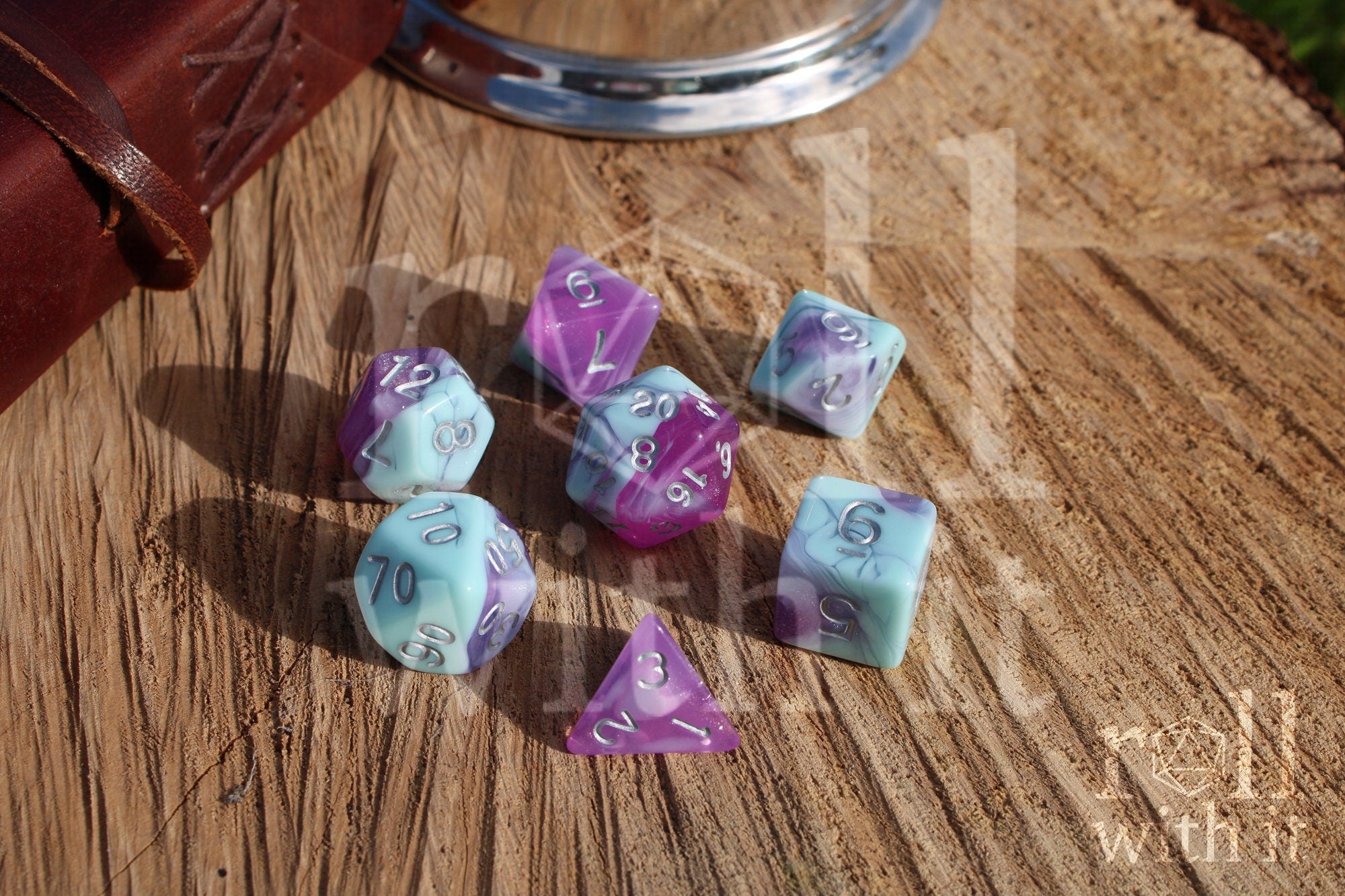 Set of 7 pastel blue marble and clear orchid purple polyhedral DND roleplaying dice on a wooden surface