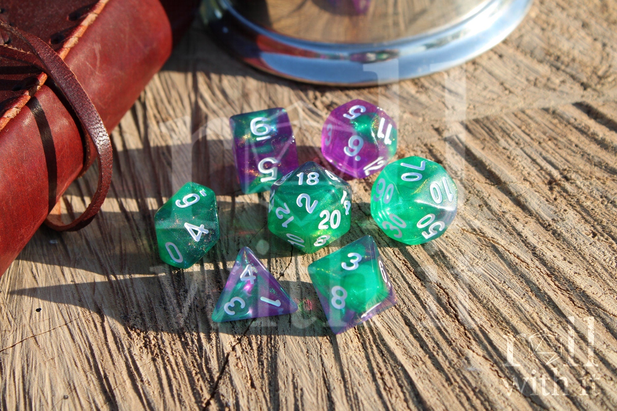 Set of colorful and glittery green and purple polyhedral dice on a wooden surface