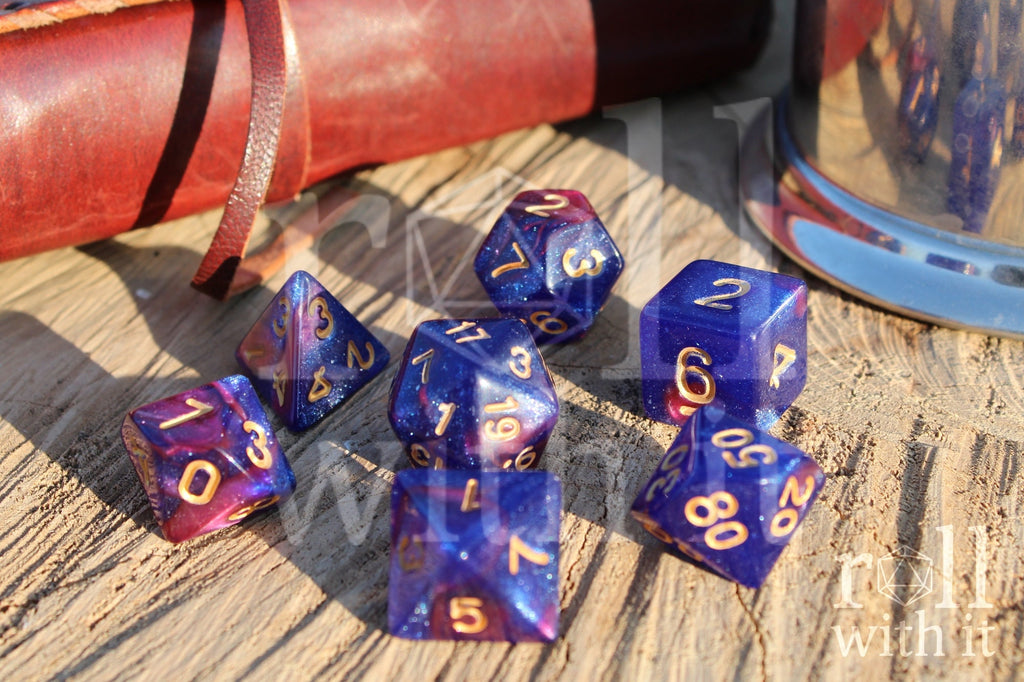 Set of purple and blue polyhedral dice with gold numbers on a wooden surface