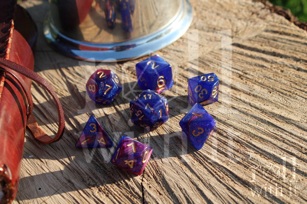 Set of purple and blue polyhedral dice with gold numbers on a wooden surface