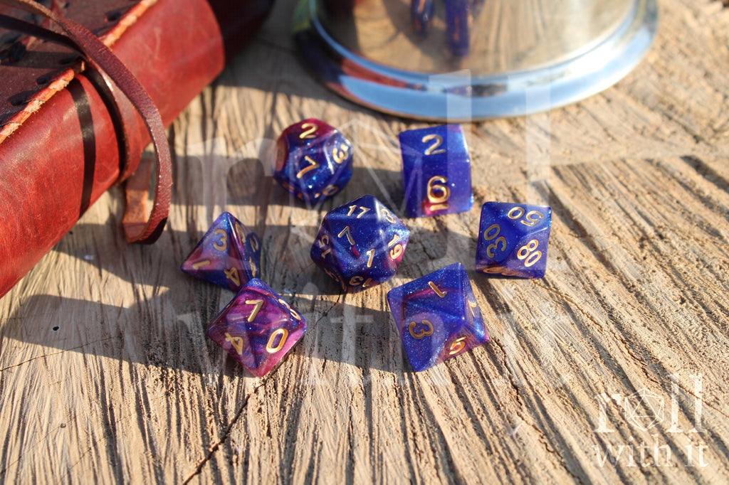 Set of purple and blue polyhedral dice with gold numbers on a wooden surface