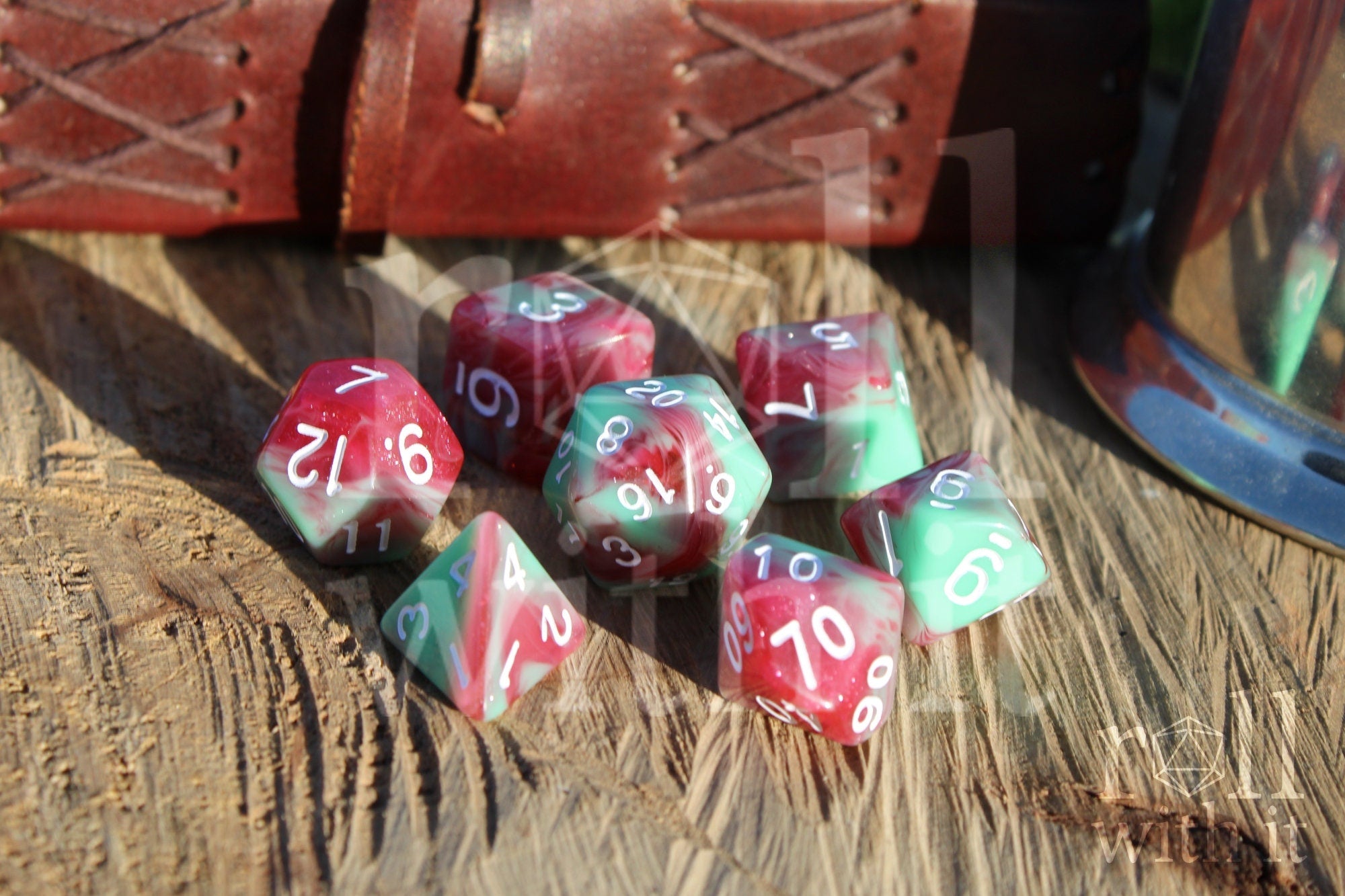 Set of glittery red and pastel green polyhedral rpg dice on a wooden surface