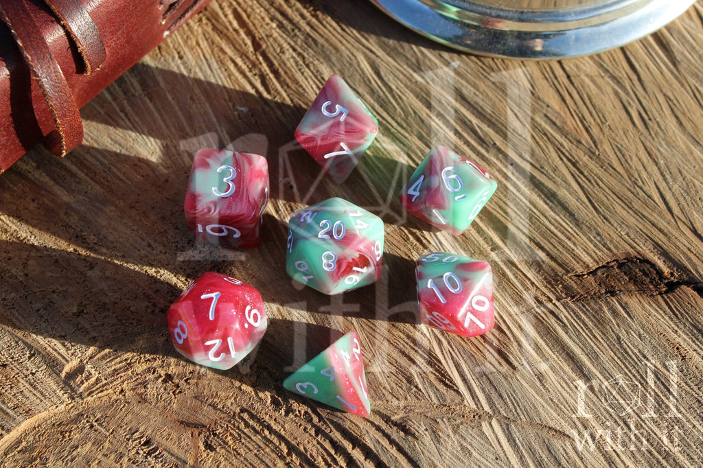 Set of glittery red and pastel green polyhedral roleplaying dice on a wooden surface