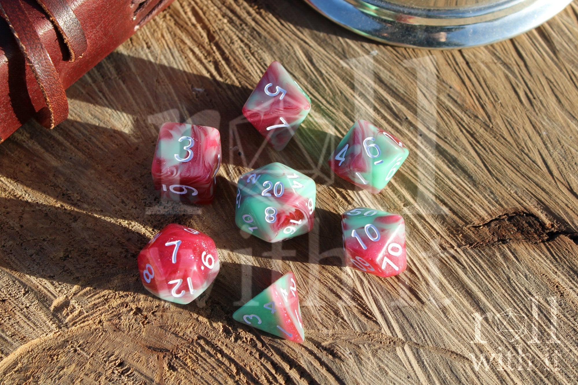 Set of glittery red and pastel green polyhedral roleplaying dice on a wooden surface