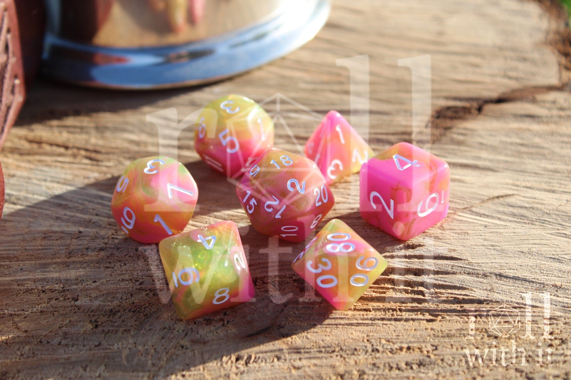 Set of candy pink and green with glitter TTRPG polyhedral dice on a wooden surface