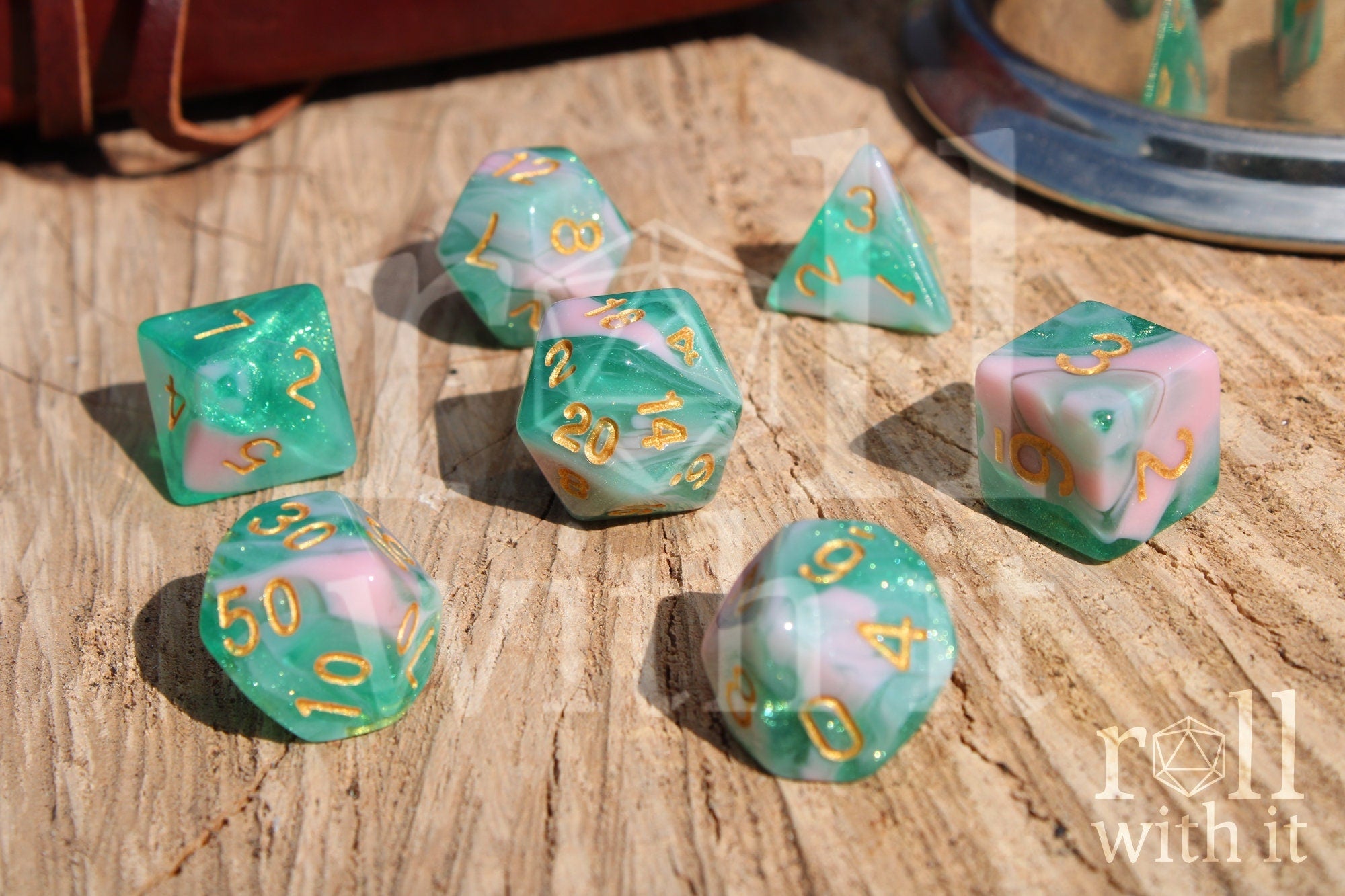Set of colorful glittery teal green and pink polyhedral dice on a wooden surface