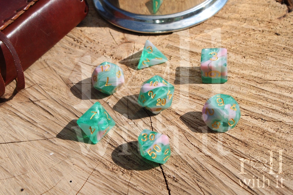 Set of colorful glittery teal green and pink polyhedral dice on a wooden surface