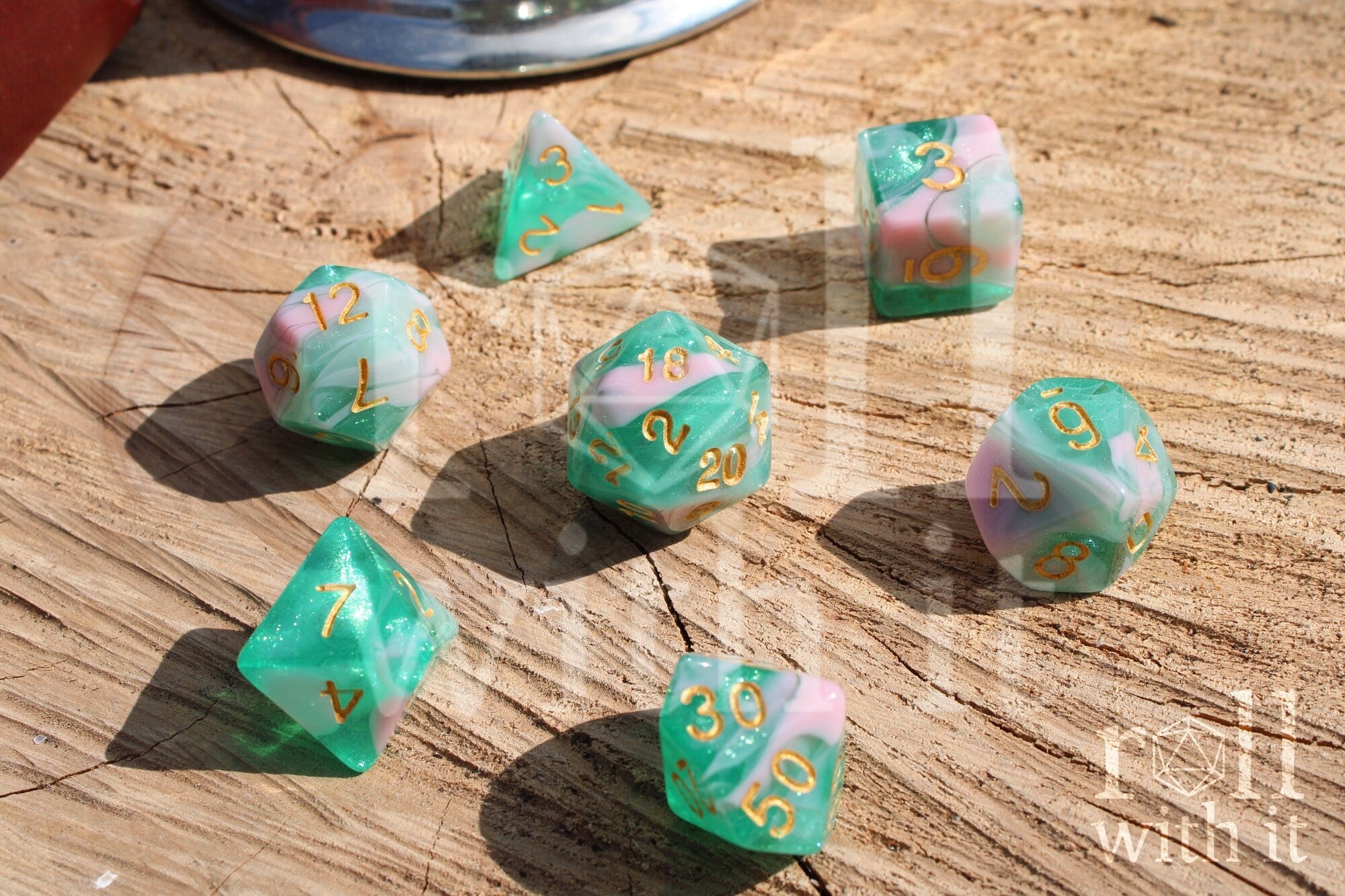 Set of colorful glittery teal green and pink polyhedral dice on a wooden surface