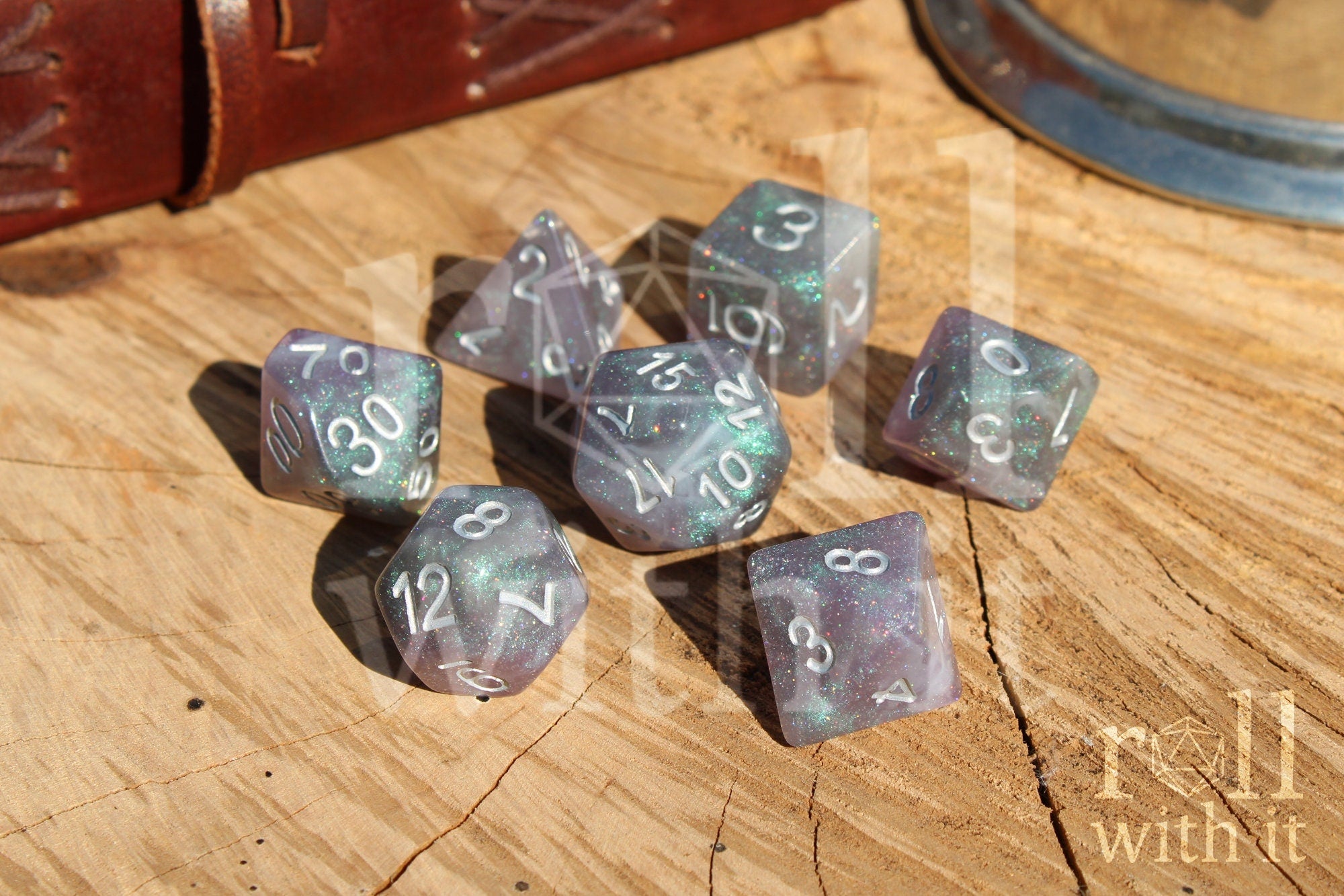Set of silver and glittery polyhedral dice with numbers on a wooden surface