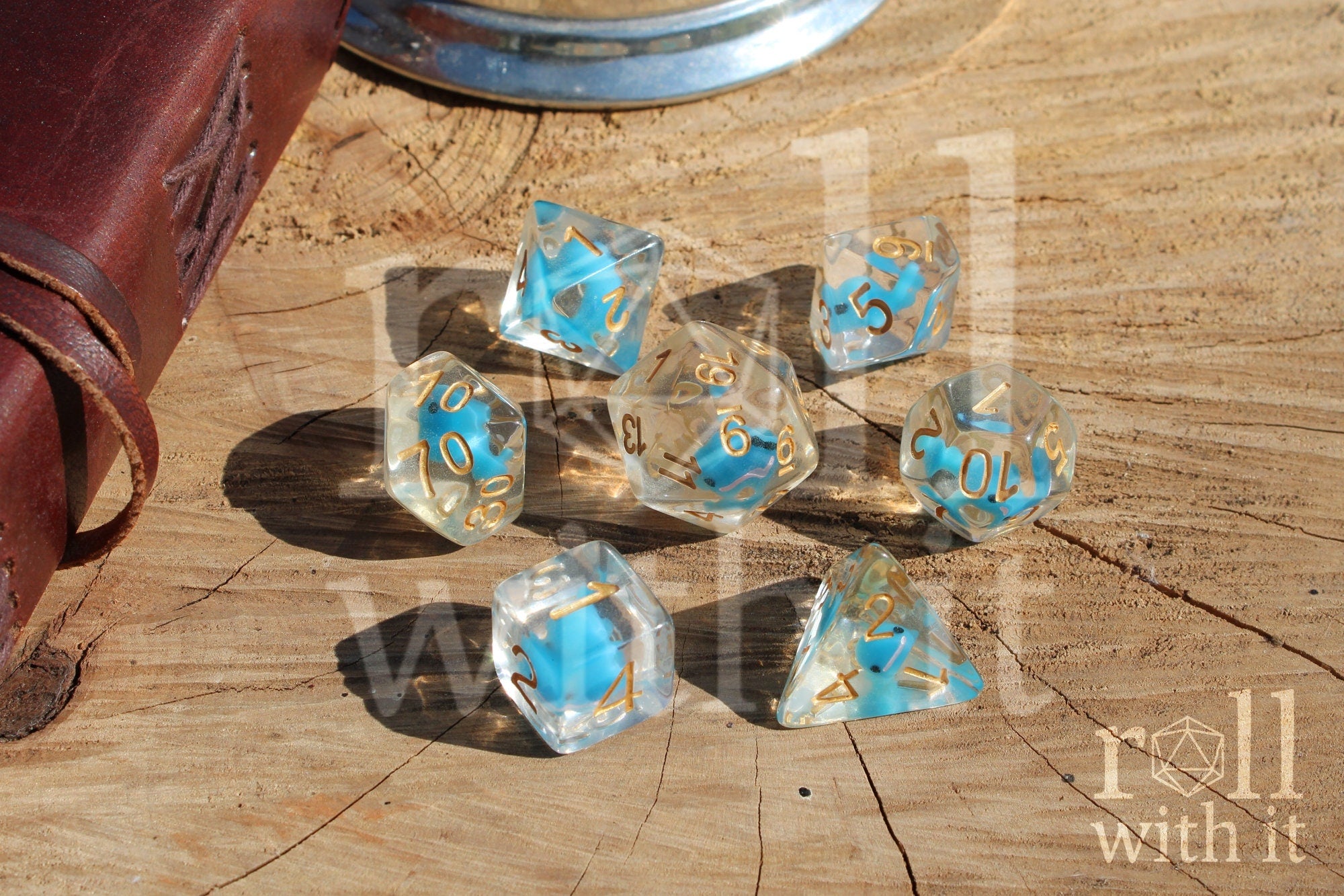Set of clear polyhedral dice with a small blue whale inside on a wooden surface