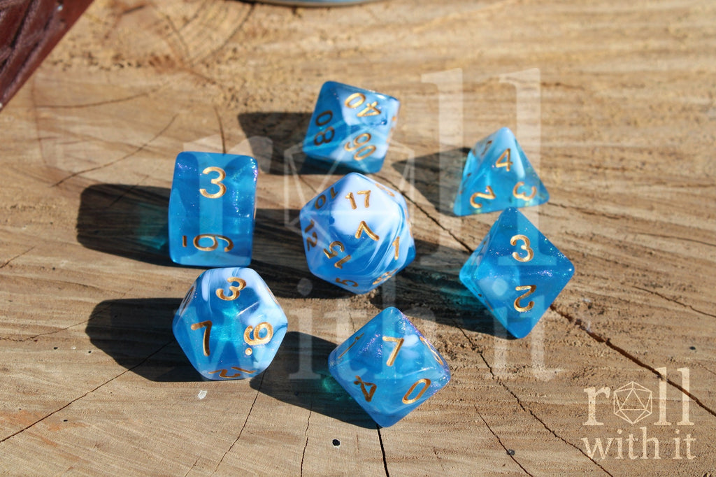 Set of blue and white glittery polyhedral dice with gold numbers on a wooden surface