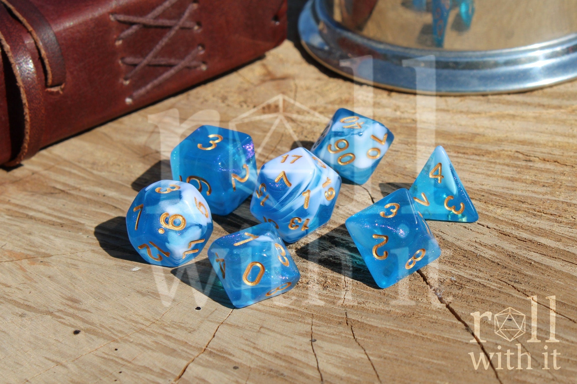 Set of blue and white glittery polyhedral dice with gold numbers on a wooden surface