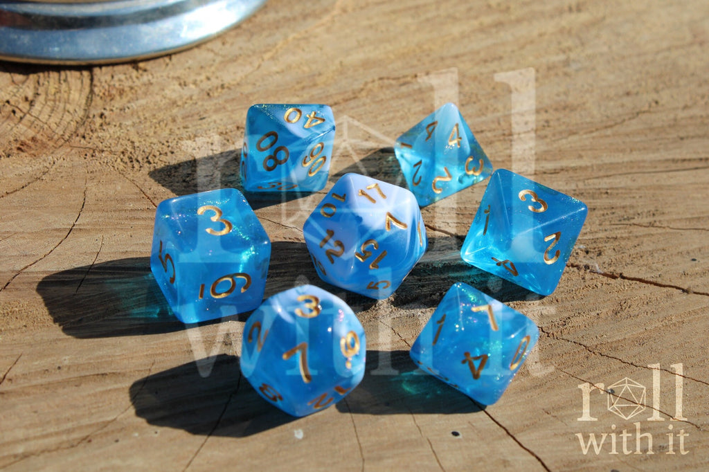 Set of blue and white glittery polyhedral dice with gold numbers on a wooden surface