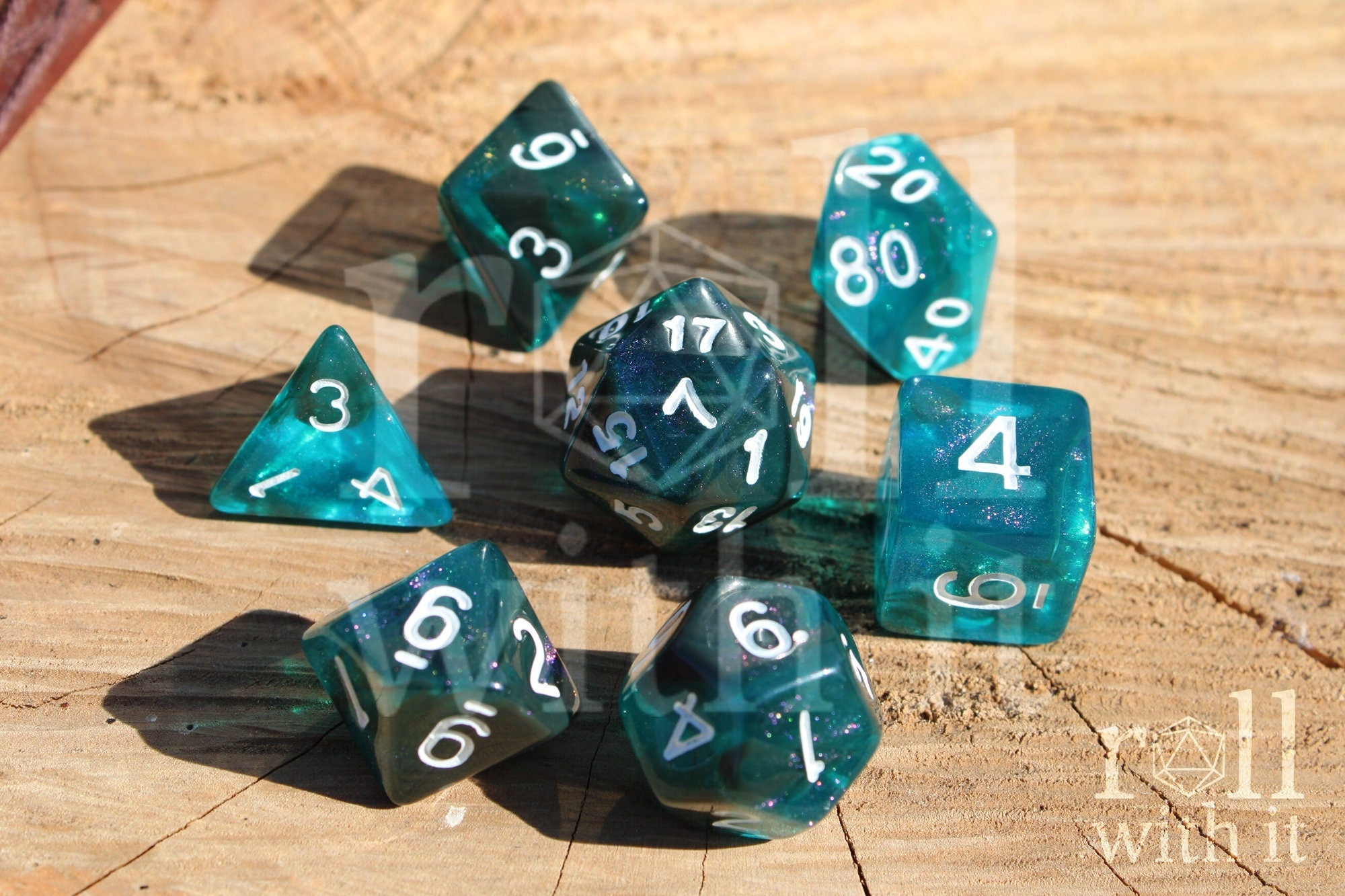 Teal and black glittery polyhedral role playing dice set on a wooden surface