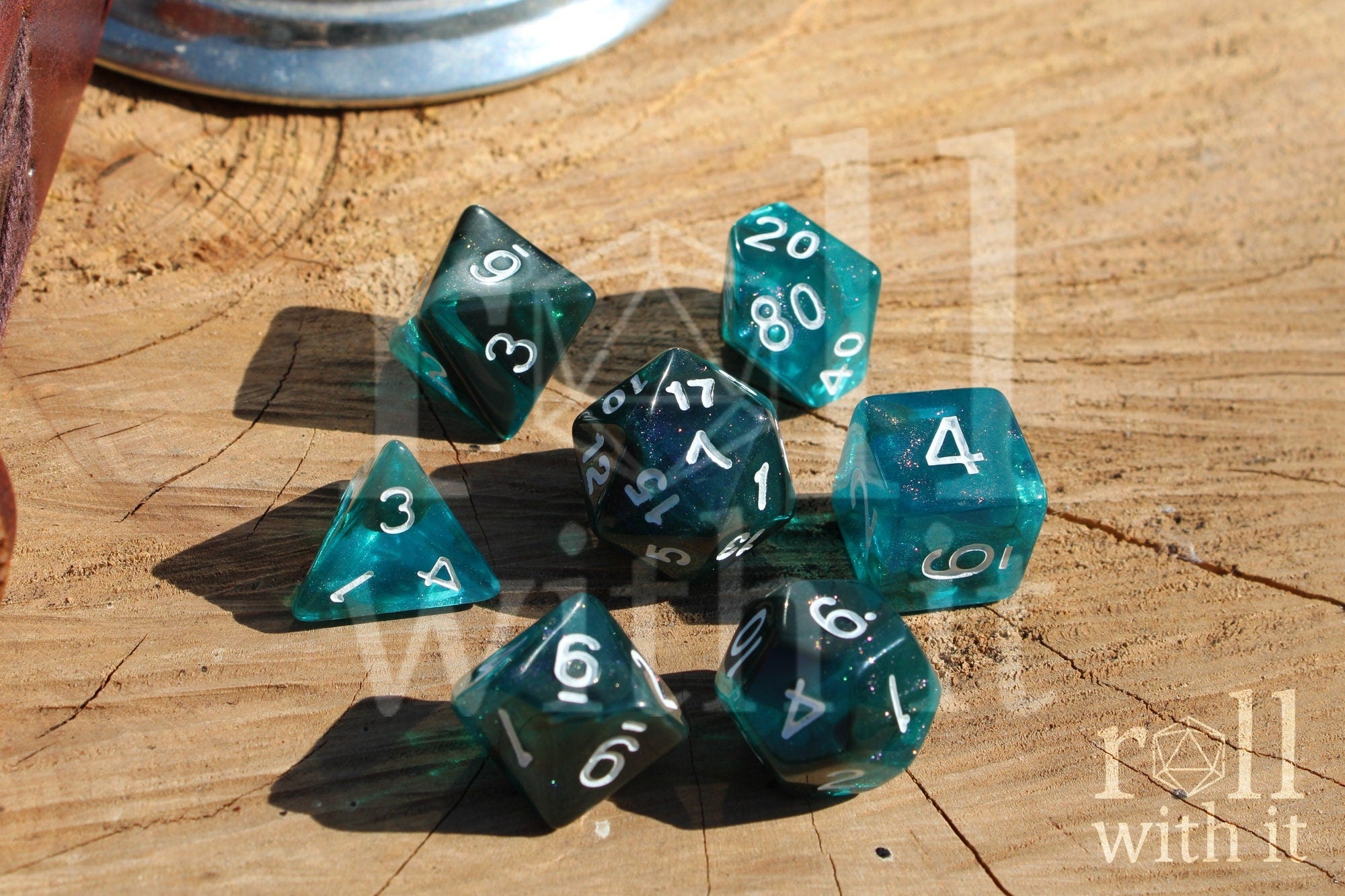 Teal and black glittery polyhedral dice set on a wooden surface