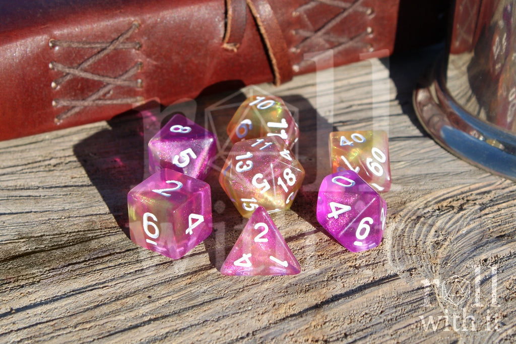 Set of colourful purple pink and yellow glittery polyhedral dice on a wooden surface