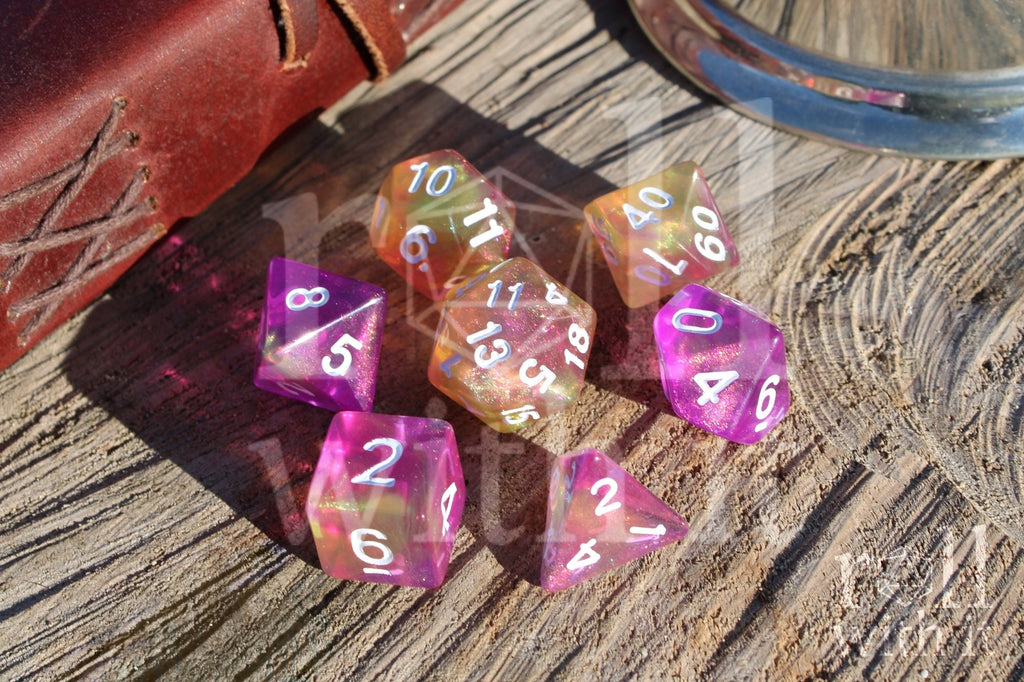 Set of colourful purple pink and yellow glittery polyhedral dice on a wooden surface