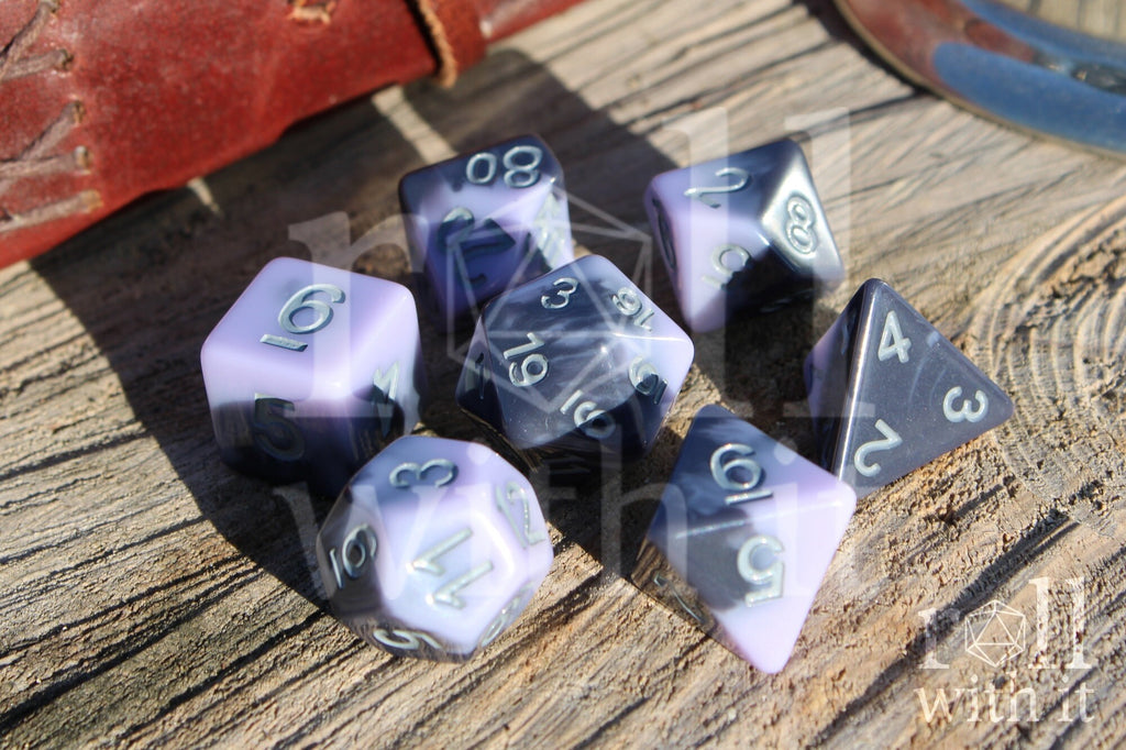 Set of pale lilac, purple and grey swirling  polyhedral roleplaying dice on a wooden surface