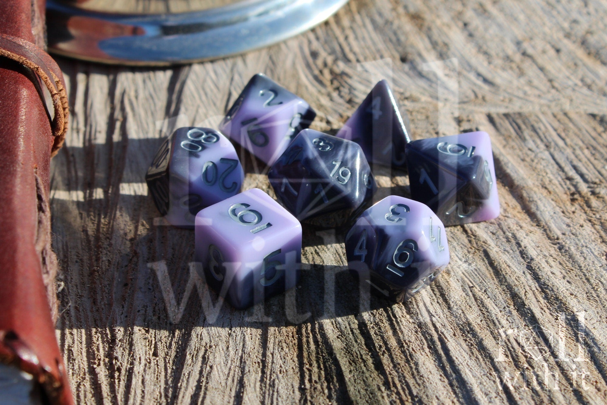 Set of pale lilac, purple and grey swirling  polyhedral roleplaying dice on a wooden surface