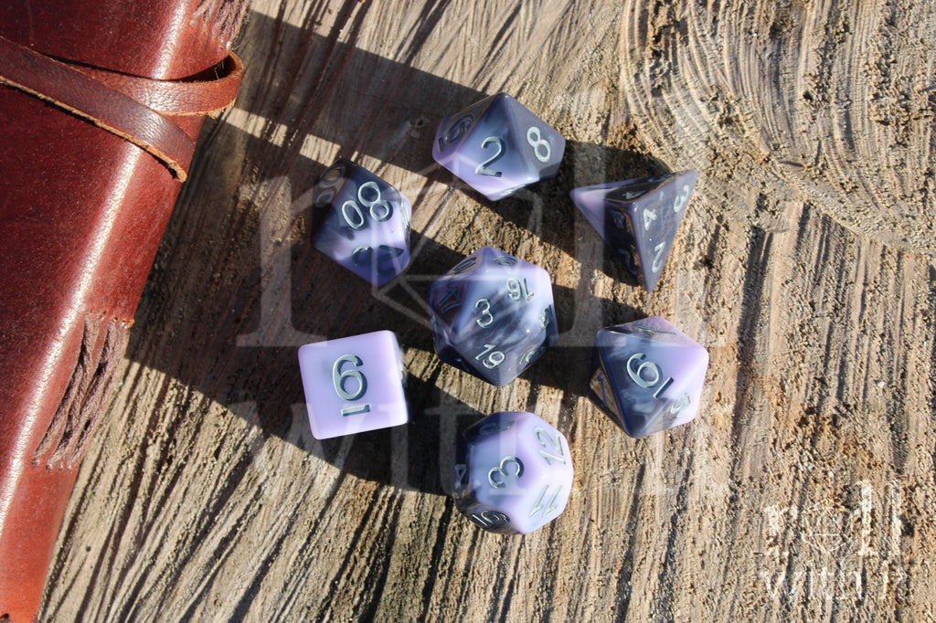 Set of pale lilac, purple and grey swirling  polyhedral roleplaying dice on a wooden surface