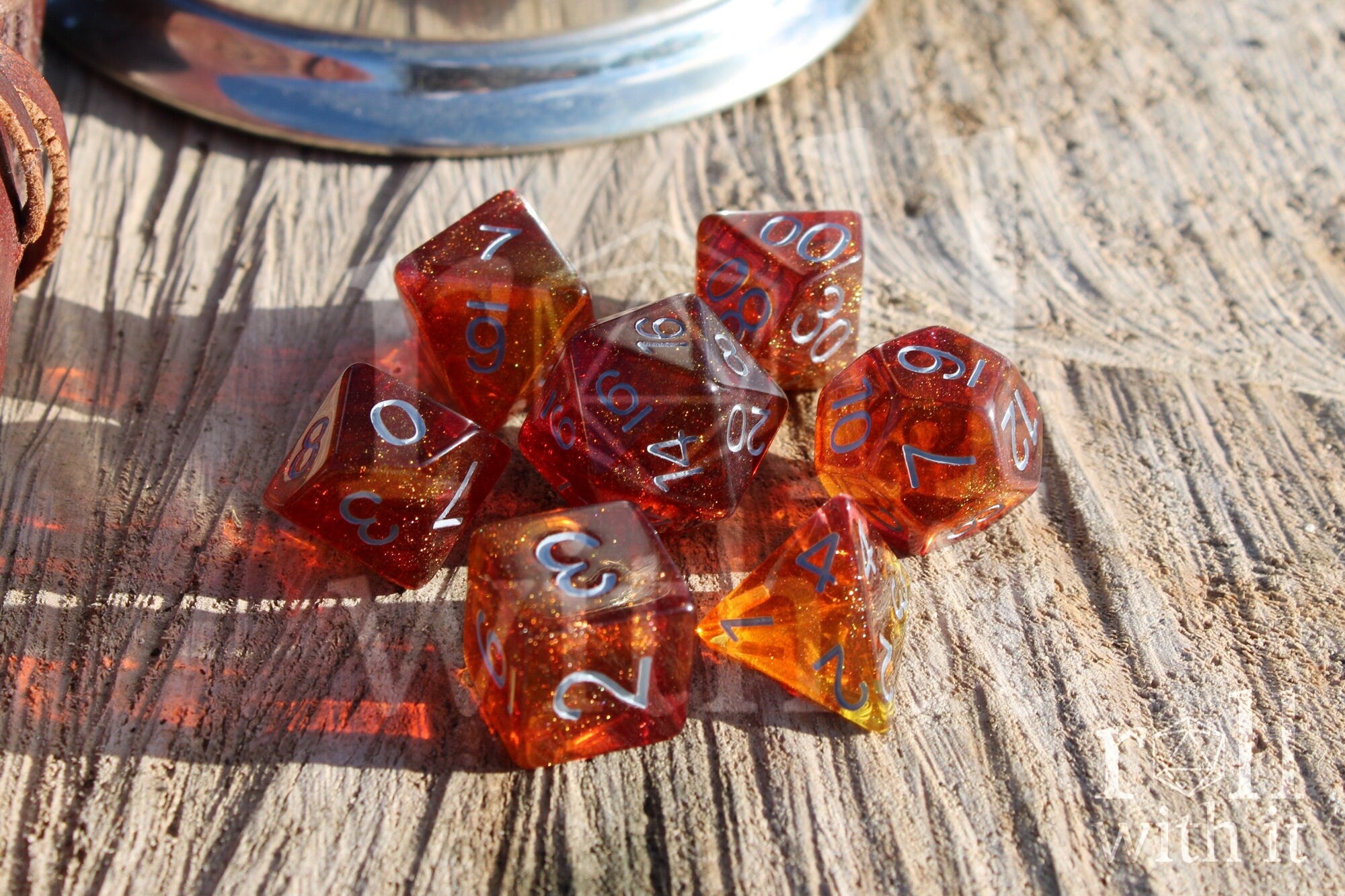 Set of vibrant and glittery red and orange polyhedral dice with white numbers on a wooden surface