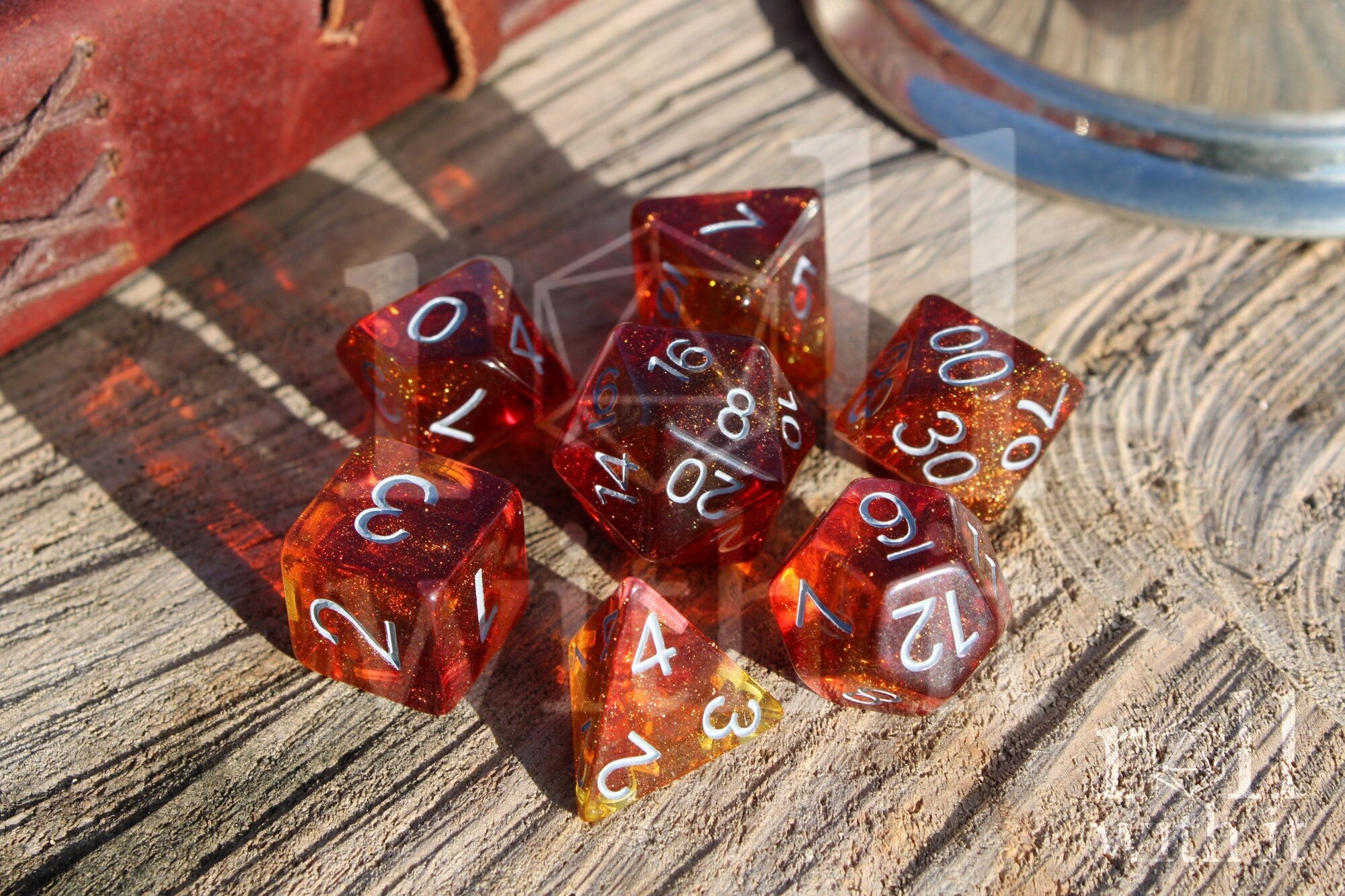 Set of vibrant and glittery red and orange polyhedral roleplaying dice with white numbers on a wooden surface