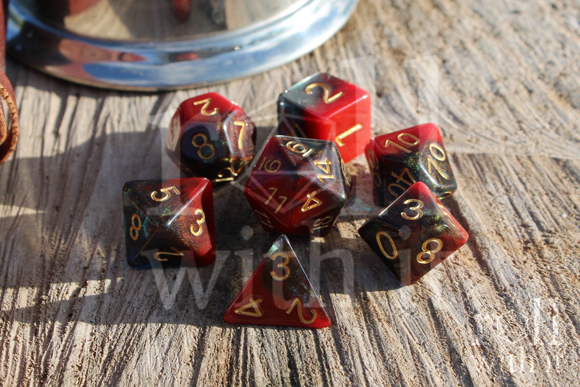 Set of colourful red and deep blue glittery polyhedral dice with gold numbers on a wooden surface