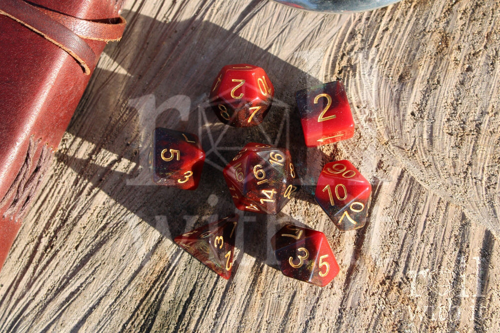 Set of colourful red and deep blue glittery polyhedral dice with gold numbers on a wooden surface