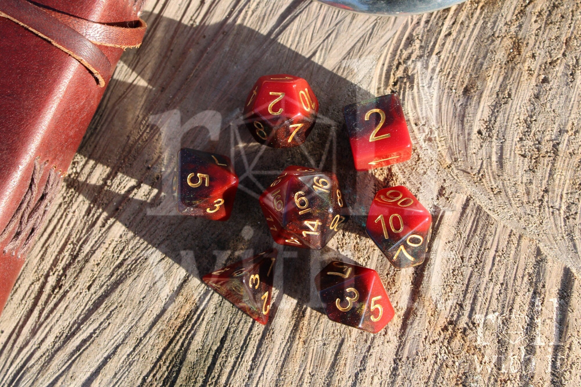 Set of colourful red and deep blue glittery polyhedral dice with gold numbers on a wooden surface