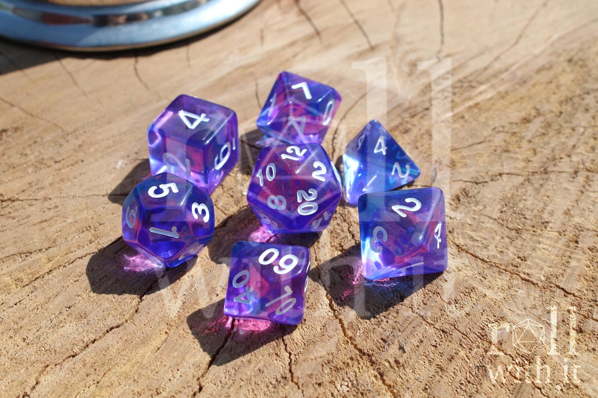 Set of clear blue and indigo purple polyhedral DND dice with white numbers on a wooden surface