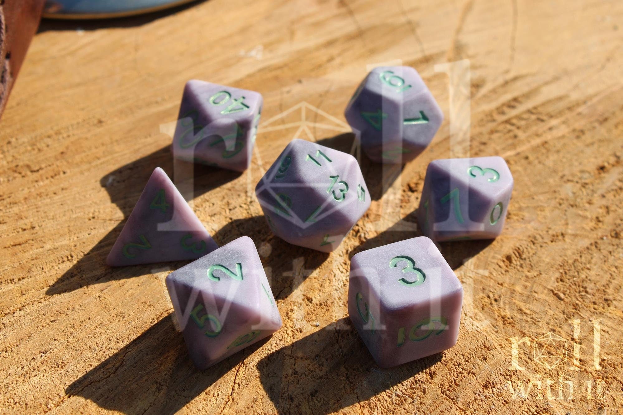 Lilac purple matte polyhedral DnD roleplaying dice with mint green numbers on a wooden surface