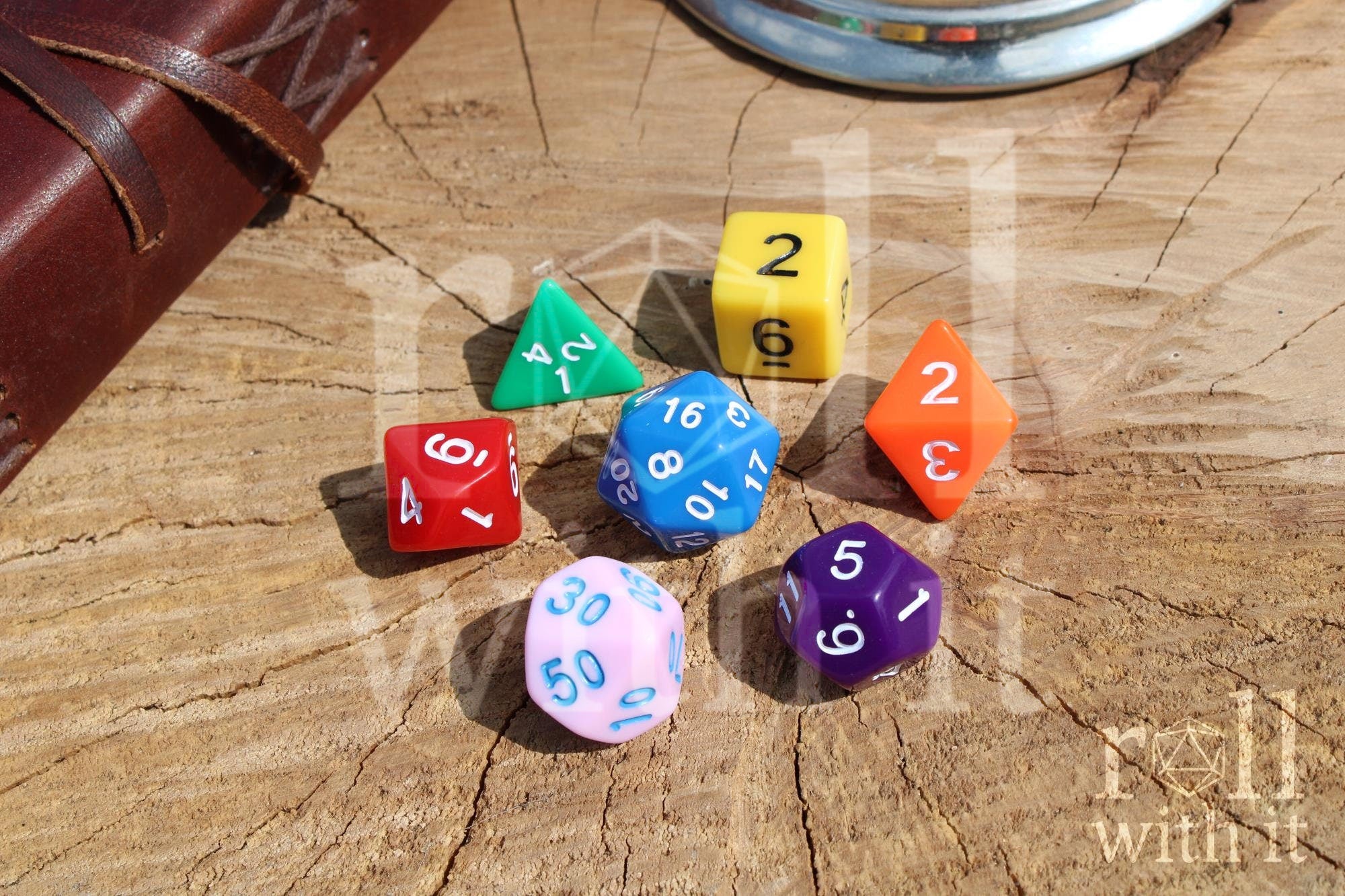A colourful rainbow polyhedral set of dice with white, blue, and black numbers on a wooden surface