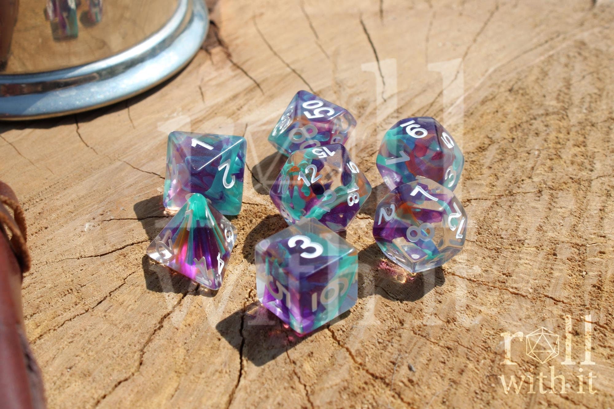 Set of 7 colourful aquamarine blue, lilac and ginger toned multicoloured polyhedral DND roleplaying dice with white numbers on a wooden surface
