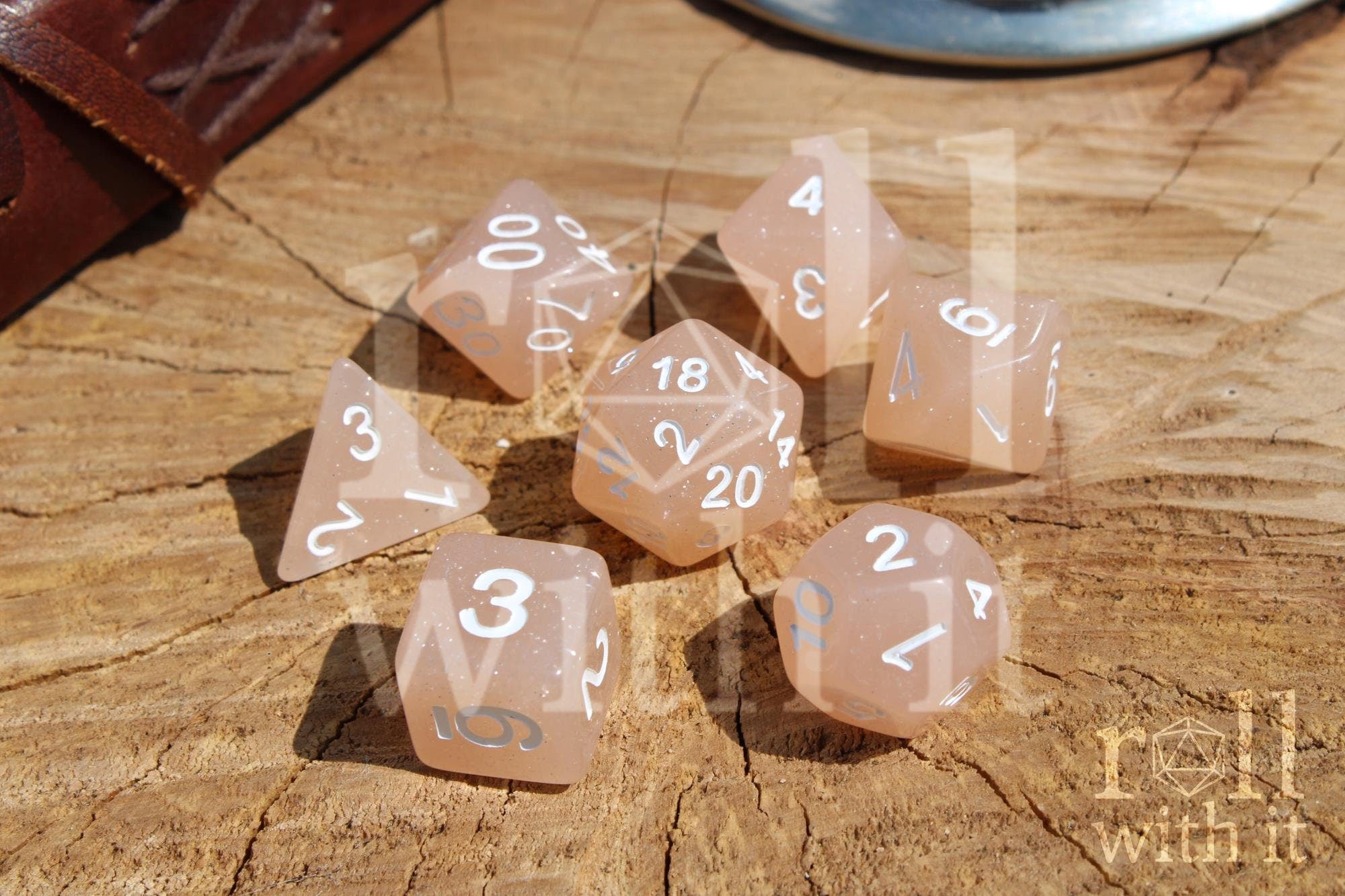 Set of creamy beige glittery polyhedral dice with white numbers on a wooden surface