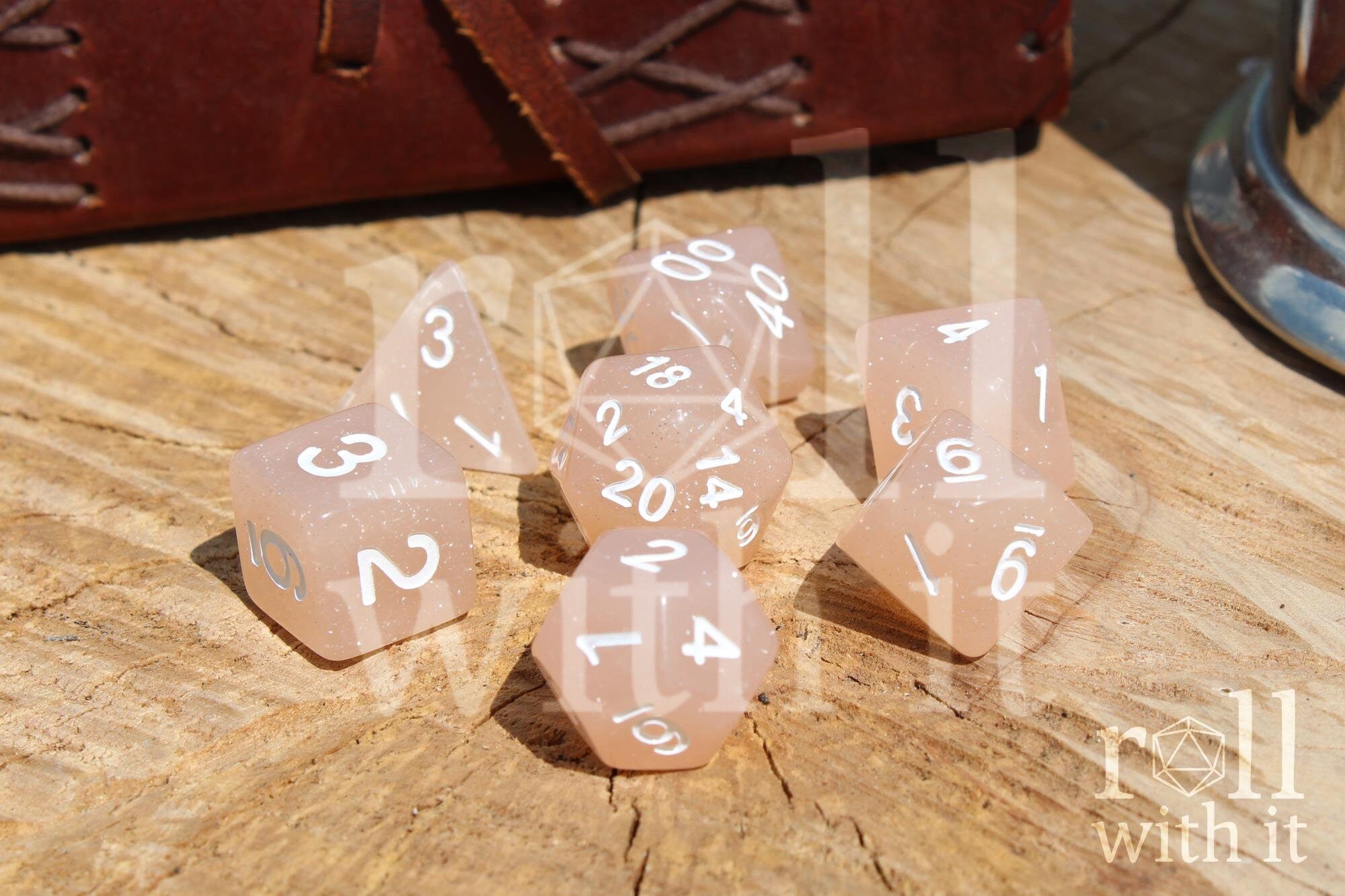 Set of creamy beige glittery polyhedral dice with white numbers on a wooden surface