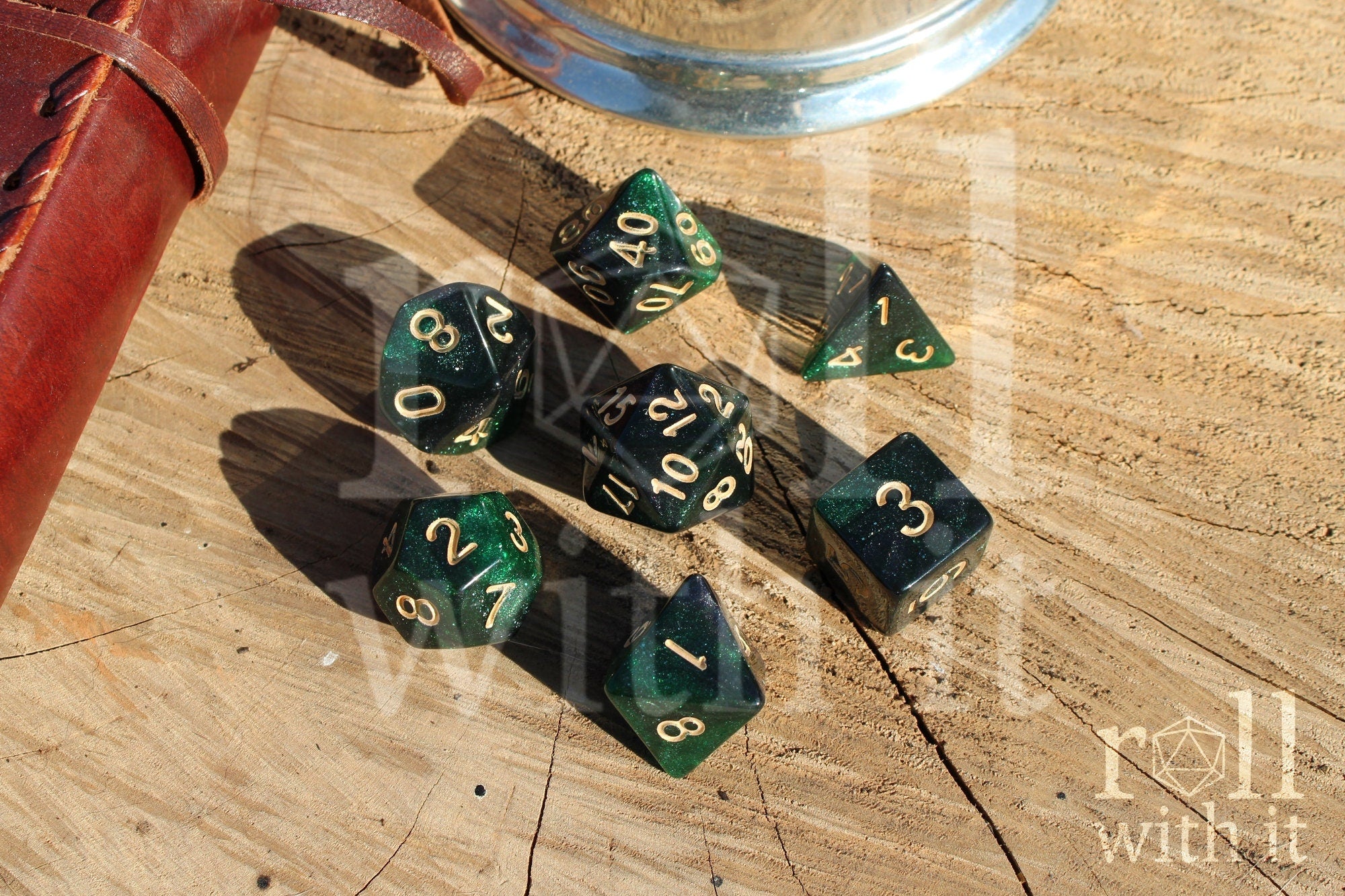 Set of starry green glittery polyhedral dice with gold numbers on a wooden surface