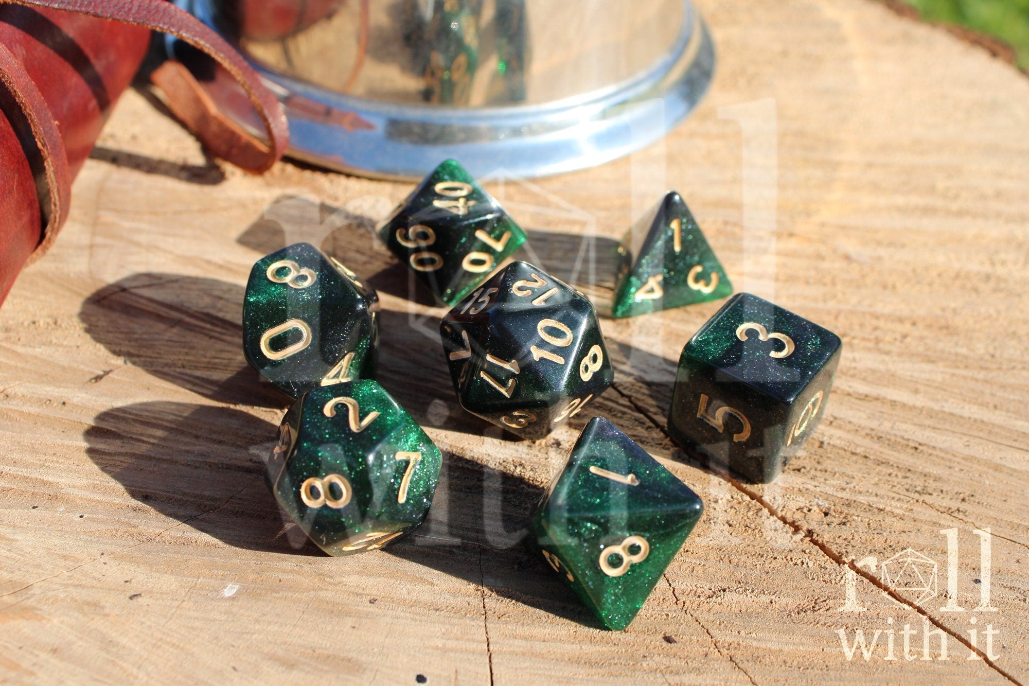 Set of starry green glittery polyhedral dice with gold numbers on a wooden surface